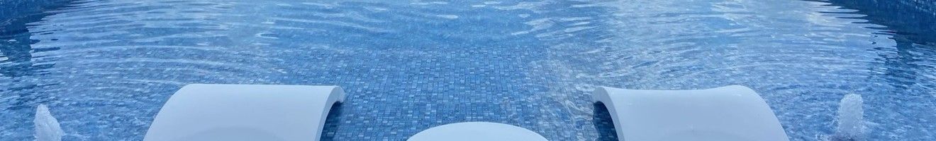 Close view of tanning ledge, loungers and bubblers in clear blue water