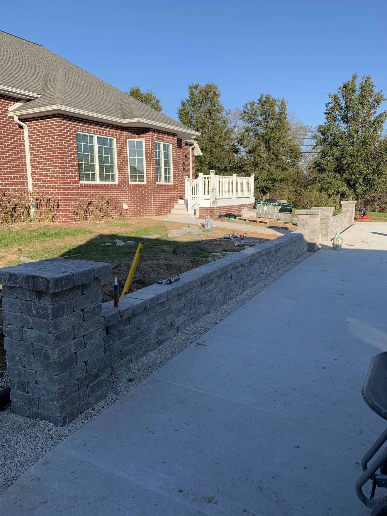 Second close-up of a gray block retaining wall and pillars beside a concrete patio